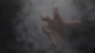 Yoğun ve kalın bir duman tabakasından uzanan bir eli tasvir eden büyüleyici ve ilgi çekici bir görüntü.