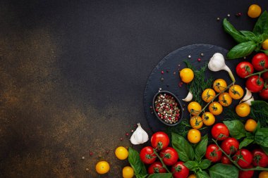 Yiyecek arka planı, taze kırmızı ve sarı domatesler, baharatlar ve fesleğen yaprakları, sarımsak ve yeşil soğanlar koyu tahtada, sağlıklı gıda konsepti, fotokopi alanı, üst görünüm