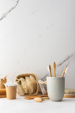 Seramik bardakta doğal tüyleri olan tahta diş fırçaları, yüz ve cilt bakım ürünleri, banyo aksesuarları, spa ve güzellik konsepti.