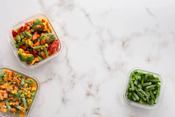 Frozen vegetables in containers , frozen cauliflower and asparagus beans, peas and corn, Brussels sprouts and carrots, mix of vegetables, top view, copy space