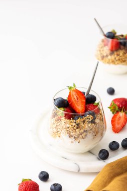 Ev yapımı granola ile yoğurtlu badem, taze çilek ve yaban mersini, lezzetli sağlıklı kahvaltı.