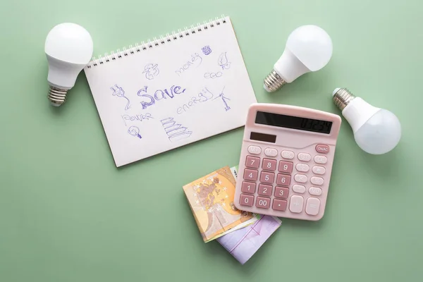 Save energy, accounting and saving money, energy saving light bulbs and notebook on a green background, money spending planning, rising electricity costs, energy crisis in Europe