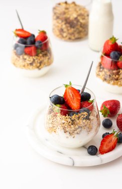 Ev yapımı granola ile yoğurtlu badem, taze çilek ve yaban mersini, lezzetli sağlıklı kahvaltı.