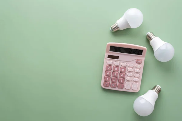 Save energy, accounting and saving money, energy saving light bulbs and notebook on a green background, money spending planning, rising electricity costs, energy crisis in Europe