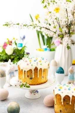Paskalya Evi 'nin içi, vazonun arka planında yumurtalar, çiçek açan kiraz dalları ve buketler dolusu çiçekler, sevimli tavşanlar olan Paskalya pastası.