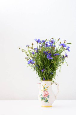 Güzel bir yaz, Centaurea, bir vazonun içinde, iç kısımlarının bir parçası olan bir vazoda üç çiçek.