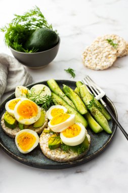 Healthy breakfasts, rice cakes with avocado and boiled eggs with dill and cucumber with spices, healthy wholesome food
