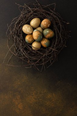 Cosmic Easter eggs in a nest on a brown background, top view, copy space
