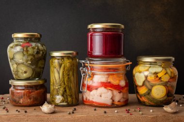 Preserving vegetables for the winter, canned vegetables in jars on a wooden table against a brown wall, pickled or fermented vegetables, copy space