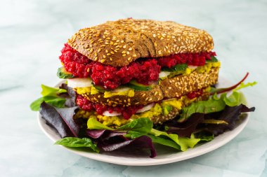 Avokado, turp ve salatalıklı sandviçler karışık salatada rendelenmiş pancar kökü mermer yeşili bir tabakta sandviçler.