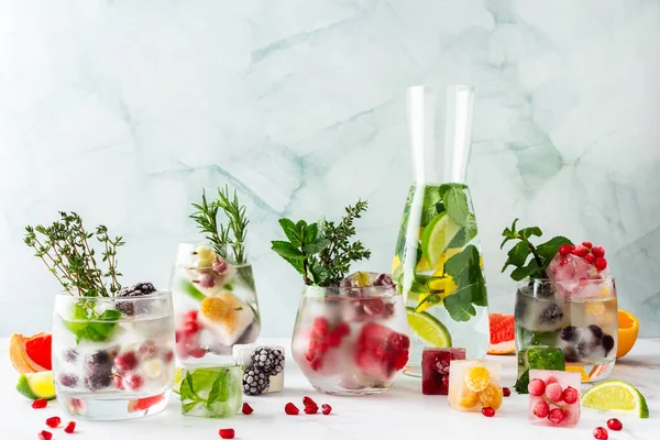 Refreshing drinks with ice cubes with fruits , ice with blackberries and raspberries, gooseberries and currants, with mint, a jug of water and citrus fruits