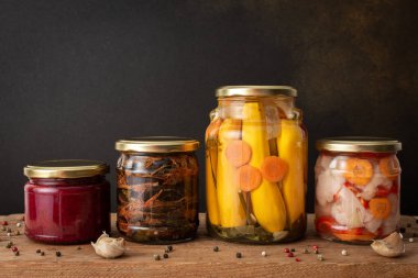 Preserving vegetables for the winter, canned vegetables in jars on a wooden table against a brown wall, pickled or fermented vegetables, copy space