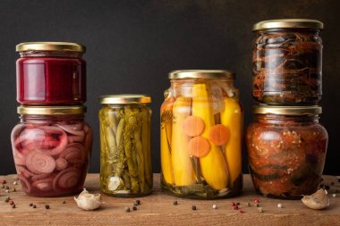 Preserving vegetables for the winter, canned vegetables in jars on a wooden table against a brown wall, pickled or fermented vegetables, copy space