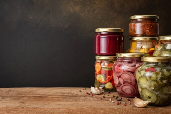 Preserving vegetables for the winter, canned vegetables in jars on a wooden table against a brown wall, pickled or fermented vegetables, copy space