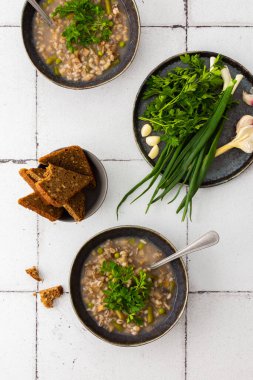 Sağlıklı öğle yemekleri, inci arpalı çorba ve kuşkonmaz ve yeşil bezelye, mantar ve patates, çorba kaseleri ve yeşil soğanlı bir tabak, sarımsak ve maydanoz, çavdar ekmeği.