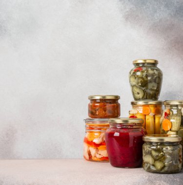 Preserving vegetables for the winter, canned vegetables in jars on a light background, pickled or fermented vegetables, copy space