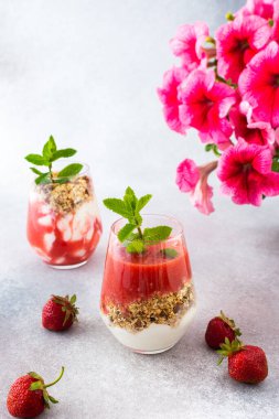 Sağlıklı lezzetli kahvaltı, müsli ve yoğurtlu bardaklar, çilekli içecekler, pembe petunyalar.
