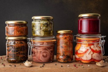 Preserving vegetables for the winter, canned vegetables in jars on a wooden table against a brown wall, pickled or fermented vegetables, copy space