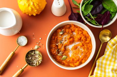 Healthy lunches, delicious pumpkin cream soup with sunflower and pumpkin seeds, sesame and flax and with coconut milk, mix salad, top view