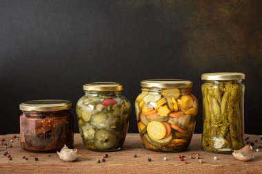 Preserving vegetables for the winter, canned vegetables in jars on a wooden table against a brown wall, pickled or fermented vegetables, copy space