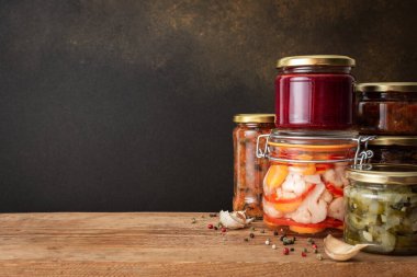 Preserving vegetables for the winter, canned vegetables in jars on a wooden table against a brown wall, pickled or fermented vegetables, copy space