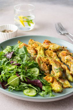 Kızarmış kabak çiçekleri hamurda ve salatayla salatalığı karıştır.