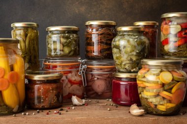 Preserving vegetables for the winter, canned vegetables in jars on a wooden table against a brown wall, pickled or fermented vegetables, copy space