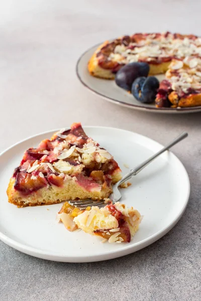 Plum cake with almond flakes, summer cake with seasonal fruits, portion of cake on a plate