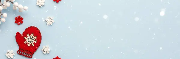 Mavi zemin üzerinde beyaz ve kırmızı kar taneleri ve beyaz böğürtlen desenli sıcak eldiven Mutlu Noeller ve yeni yıl afişi, üst manzara, kopyalama alanı