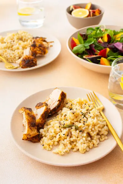 Delicious hearty lunch, brown rice with baked chicken breast and seeds, mixed salad with figs and peach