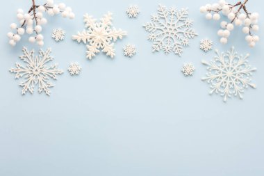 Mavi arka planda beyaz kar taneleri ve rowan dalları, Noel arkaplanı, Mutlu Noeller ve Mutlu Yıllar konsepti, üst manzara, kopyalama alanı