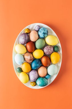 Turuncu arka planda doğal boyanmış Paskalya yumurtaları ile oval tabağın en üst görüntüsü, Mutlu Paskalyalar.