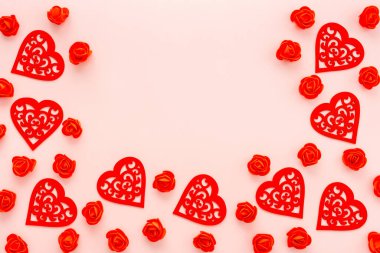 Pembe arka planda dekoratif kırmızı çiçekler ve kalpler. Sevgililer Günü ya da düğün, üst manzara, kopyalama alanı konsepti.