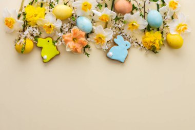 Bahar çiçekleriyle, doğal renklerde yumurtalarla, Paskalya tavşanlarıyla, beyaz nergislerle ve sarı pastel arka planda kiraz çiçekleriyle süslü bir arka plan.