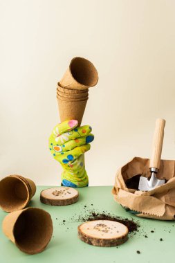 Tohumlar için domates tohumu ekmek, saksıları, çevre dostu çömlekleri ve tohumları olan bir eldiven vermek, yeşil arka planda yer ve bahçe aletleri, bahar baharı baharı için hazırlık