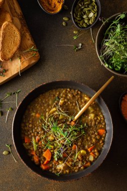 Sağlıklı vejetaryen yemekleri, domatesli kahverengi mercimek çorbası, havuç, patates ve köri baharatı, kızarmış ekmek, kahverengi arka planda kesme tahtasında çorba.