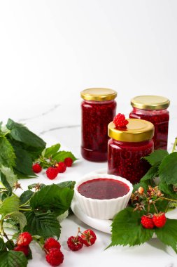 Ev yapımı yaz koruma, kavanozlarda ahududu reçeli, reçelli kavanozlar ve ahududu filizleri.