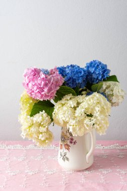 Güzel bir yaz buketi pembe, leylak ve vazoda beyaz ortancalar, rahat ev içleri, pembe masa örtüsü ve vazoda bir buket çiçek.