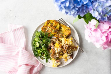 Sağlıklı kahvaltı, kızarmış mantarlı omlet, roka salatası, salatalık ve çeşitli tohumlar, kızarmış kabak gözlemesi, bir buket ortanca.