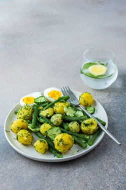 Lezzetli öğle veya akşam yemeği, kuşkonmaz fasulyeli haşlanmış taze patates ve taze salatalık, haşlanmış yumurta ve taze böğürtlen, limon ve nane ile ferahlatıcı su.