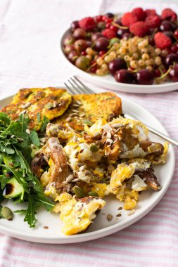 Sağlıklı kahvaltı, kızarmış mevsimlik orman mantarlı omlet Chanterelles, roka salatası, salatalık ve çeşitli tohumlar, yeşillikli kızarmış kabak gözlemesi.