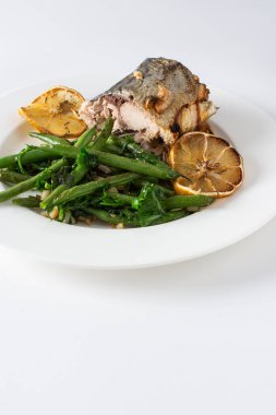 Soğanlı ve fırınlanmış uskumrulu fırınlanmış taze fasulyelerin lezzetlerinin tadını çıkarın. Beyaz arka planda zarif bir tabakta, besleyici ve lezzetli bir akşam yemeği ya da öğle yemeği için ideal.