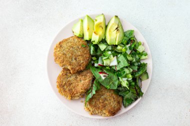 Kinoa pirzolası, avokado ve turpla karışık salata, limonlu kivi ve su, lezzetli, sağlıklı kahvaltı, vejetaryen yemek tabağı.