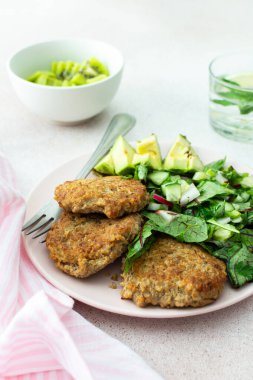 Kinoa pirzolası, avokado ve turpla karışık salata, limonlu kivi ve su, lezzetli, sağlıklı kahvaltı, vejetaryen yemek tabağı.