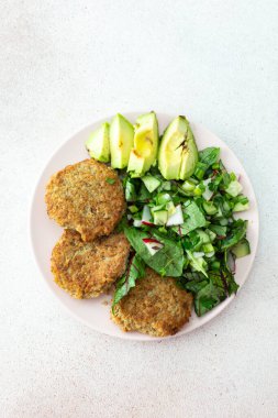 Kinoa pirzolası, avokado ve turpla karışık salata, limonlu kivi ve su, lezzetli, sağlıklı kahvaltı, vejetaryen yemek tabağı.