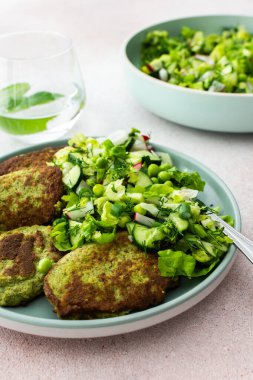 Kabak ve brokoli krepleri salatalık, taze bezelye ve turptan oluşan karışık bir salata ile servis ediliyor. Bu sağlıklı vejetaryen yemeği hem lezzetli hem de besleyicidir.