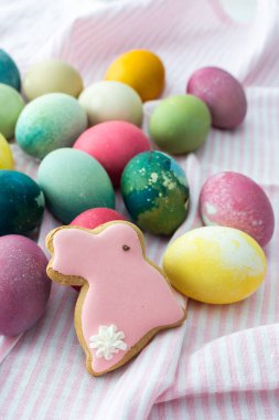 Çok renkli Paskalya yumurtaları, pembe masa örtüsü üzerinde dekoratif tavşanlar, Paskalya tatiliniz kutlu olsun.