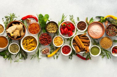 Gri arka planda çeşitli baharat ve otlardan oluşan bir koleksiyon. Lezzetli ve dokulu yemekleri geliştirmek için mükemmel.