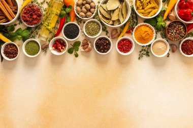 Sıcak bej bir zemin üzerinde canlı baharat ve otların çeşitli çeşitleri, mutfak ilhamı için doğal ve aromatik bir palet sergilenmektedir, üst görünüm, kopyalama alanı