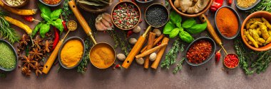 Kahverengi bir yüzeye karşı dizilmiş baharat ve otların zarif bir düzeni, aromatik zenginliklerini, görsel çeşitliliklerini, afişlerini vurguluyor.